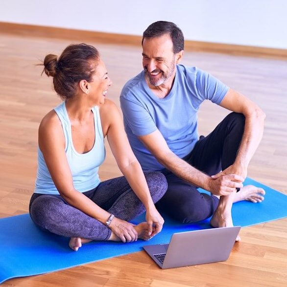 man in white tank top and gray pants sitting on blue yoga mat